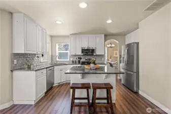 Large open kitchen with updated, stainless appliances, and island flowing to the family room and backyard patio.