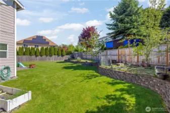 Large, fully fenced backyard with raised garden bed, patio, shed; ready for pets and yard toys.