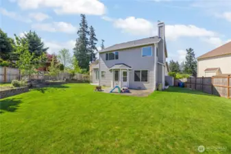 Large, fully fenced backyard with raised garden bed, patio, shed; ready for pets and yard toys.