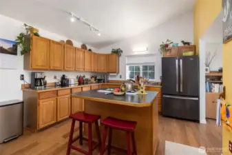 Spacious kitchen with wood cabinetry, center island.  Dining room through the opening at right.