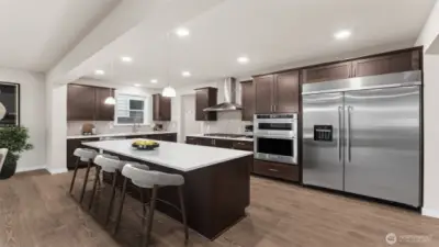 Gourmet kitchen with large center island, quartz counters, loads of cabinets, built-in 48" fridge and in-wall oven & microwave next to your large family room. Actual home is under construction and materials, colors, and finishes will vary. See site agent for details.