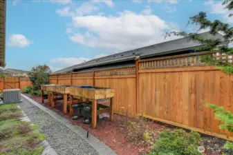 Side of home, fully fenced in back yard, beautifully landscaped, & raised garden beds