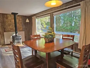 The living room features these huge picture windows and a wood stove for cozy nights in.