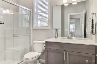 This main floor bathroom is designed with style and functionality, featuring a sleek stand-up shower, elegant quartz counters, and wood-wrapped windows that add a warm, sophisticated touch. A perfect blend of modern finishes and timeless details!