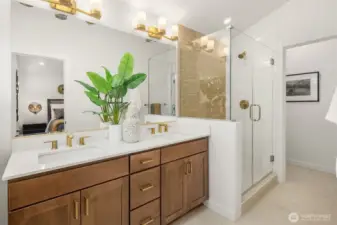 Primary bath with dual sinks and fully tiled shower with frameless glass enclosure.