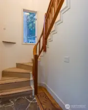 Stone floored entry way meets inlaid hardwood floors that have recently been refinished, and the stairway leading up the second floor