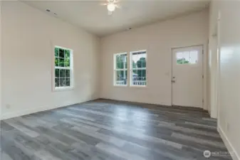 Front door into living room with ceiling fan