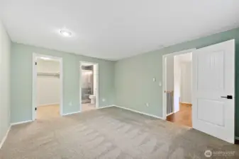 Primary suite with carpeted flooring, featuring a walk-in closet, en-suite remodeled 3/4 bath