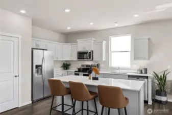 Large kitchen features shaker style cabinets with soft close doors and quartz countertops. Actual home is under construction. Colors, materials, and features may vary. See site agent for details.
