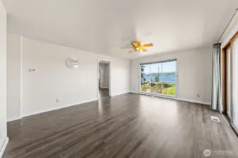 A spacious living room features large picture windows that fill the space with natural light, along with a glass slider offering another easy access point to the yard.