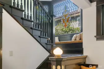 Light pours through the magnificent stained-glass window above the stairway, creating a perfect nook for the built in bench