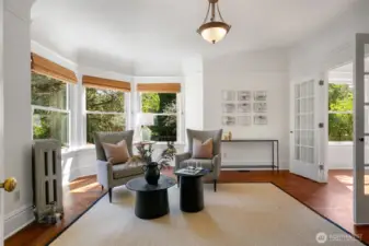 A bright study/library with soaring ceilings custom built-ins and french doors that lead to the living room