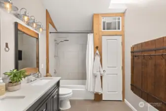 Gorgeous & spacious guest bath with high ceilings, stunning natural light via skylight, linen closet, double vanity, and heated floors!