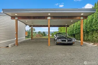 Covered timber-frame carport with recessed lighting and water views through the structure