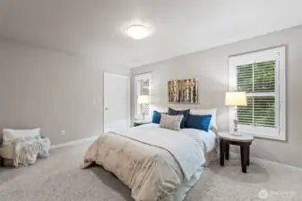 Primary bedroom is private yet well-lit, with custom shutters. Door leads to laundry room.