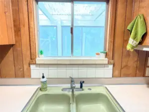 Window over kitchen sink looking out to enclosed porch and backyard.