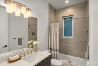 Second floor bathroom features a ceramic tile walk-in shower and white quartz countertop