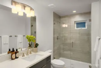 First floor bathroom features a ceramic tile walk-in shower and white quartz countertop.