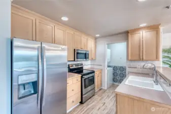 The kitchen is adorned with sparkling stainless appliances, newer kitchen faucet 2023, oak cabinetry with crown molding and a convenient pantry with built-in shelving.