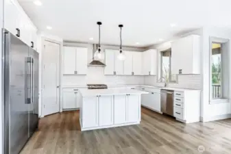 The open concept Great Room offers a sleek kitchen with high-end appliances, modern subway tile backsplash, large island with eating area area, glass pendant lighting and lots of natural light that floods into this space.