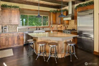 Featuring rich knotty alder distressed cabinets, sleek quartz surfaces, artisan hardware, and a classic farmhouse sink, the kitchen blends rustic charm with contemporary sophistication for both everyday comfort and memorable gatherings.