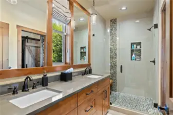 The primary bath boasts a double vanity paired with a textured pebble-stone shower.