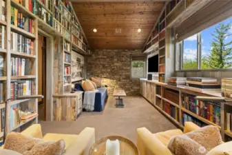The upper-level bonus room serves as both a library and guest suite, featuring custom reclaimed wood bookshelves and stone accents.