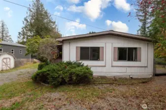 View of the home from the west side.  Access gate to the backyard makes it a great space for pets....perfect dog run area.  Large garden storage shed to he left of the home as well as another fenced area for a garden or wood pile.