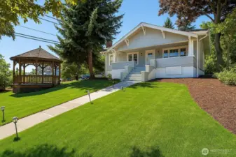 The east façade showcases a stately approach, with grand front stairs and a gracefully designed walkway. Photos from earlier listing in 2025. Green grass rendered virtually.