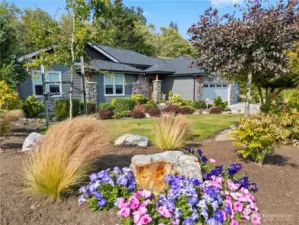 Showcasing refined Northwest craftsmanship, this beautifully landscaped home pairs stone accents and lush gardens with a welcoming design that feels both polished and peaceful.