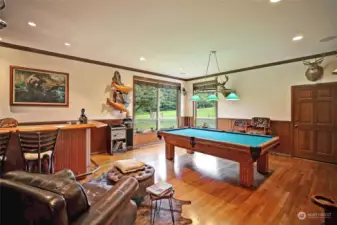 Main floor stunning Den/Game room with large windows, custom pool table, wet bar, French doors, and access to back patio!