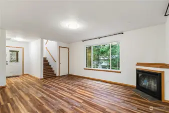 Living room with large windows overlooking woods.  Propane fireplace.