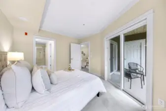 Primary bedroom view to the balcony slider living area and primary bathroom
