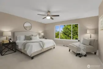 Spacious primary bedroom with large window, seating area, and serene views.