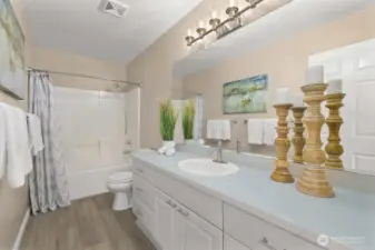 Full hall bathroom with long vanity, updated lighting, and tub/shower combo.