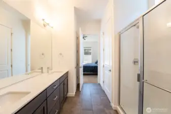 Beautiful tiled primary bath with walk-in shower, double vanity, private toilet, linen closet, and walk-in closet.