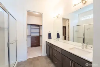 Primary bath with walk-in shower, double sinks, walk-in closet, linen storage, and private toilet.