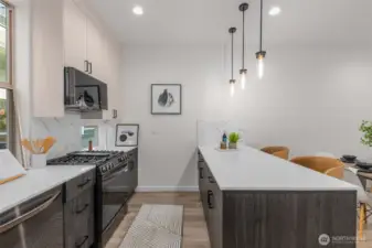 Photos of Model Home. Alternate kitchen view highlighting pendant lighting, stainless steel appliances, and thoughtful layout. Every detail reflects modern efficiency.
