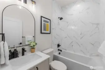 Photos of Model Home. Designer bathroom wrapped in floor-to-ceiling tile with a luxurious soaking tub, crafted for evenings of relaxation and self-care.