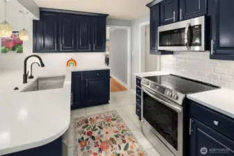 Beautifully updated kitchen features quarts countertops, stainless steel appliances, and custom pendant lighting