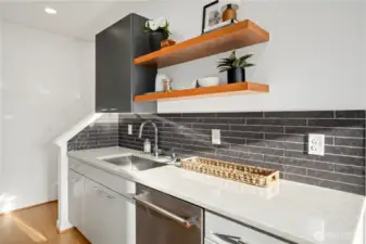 Beautifully designed kitchen features SS KitchenAid appliances, tile backsplash, under mount lighting, custom floating shelves, quartz counters and space to cook up a delicious meal for guests.