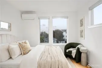 Corner primary bedroom with hardwood floors and lots of natural light.