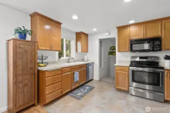 Through that doorway, there is a pantry to the left. The staircase branches off, with one bedroom up the staircase to the right, the garage just past that on the right, and the staircase down to an entire daylight basement downstair.