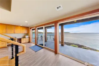 Downstairs is accessed via beautiful wood steps leading to large multi purpose flex space perfect for home office, recreational room, home gym and more. Glass doors lead out to the covered waterfront space.