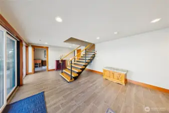 View looking back at the wood staircase leading to the lower level. Warm wood detailing and porcelain tile floors continue downstairs.