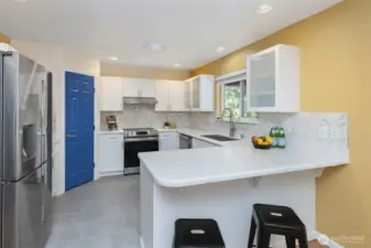 2nd home kitchen with solid surface counter tops, tiled backsplash, new appliances and tile floor.