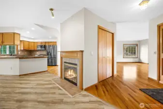 Interior entry view highlighting multiple living spaces, kitchen, with a central fireplace feature. Entry door on the right.
