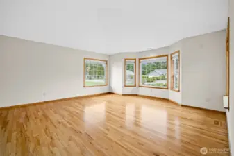 Living room located to the right of the entry featuring hardwood floors and multiple windows providing natural light.