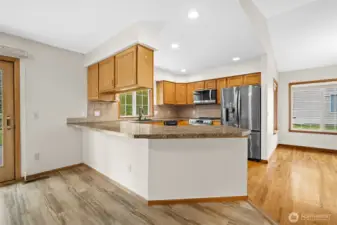 View from the family room toward the kitchen highlighting seating, open sightlines and adjacent dining space.