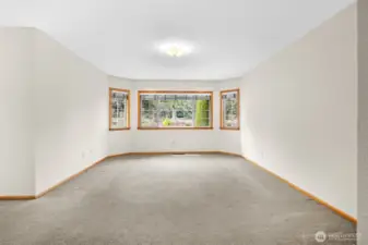 Spacious primary bedroom featuring a bay window with views of the yard and abundant natural light.
